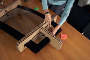 Paper honeycomb packaging being shaped by a packaging engineer for automotive windshield protection.